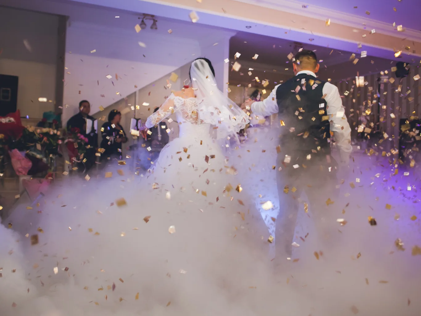 A dj working on a residential ceremony and reception music job — mid-task, hands, tools and the work itself in sharp focus, the rest of the space softly out of focus
